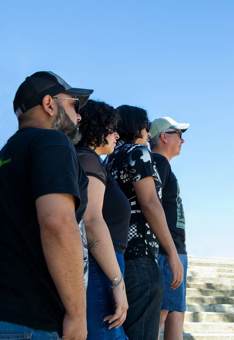 Cuatro integrantes de una banda de perfil contra el cielo