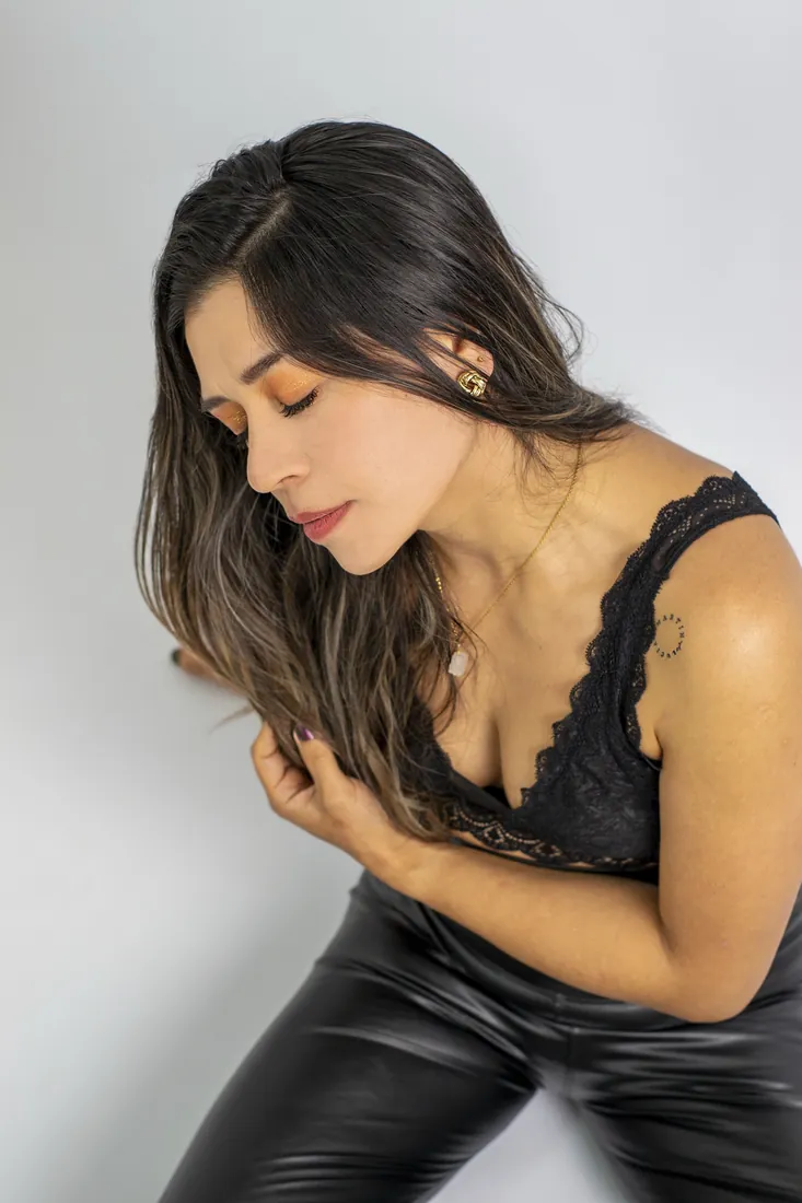 Mujer de pelo largo con la mirada baja sobre fondo claro