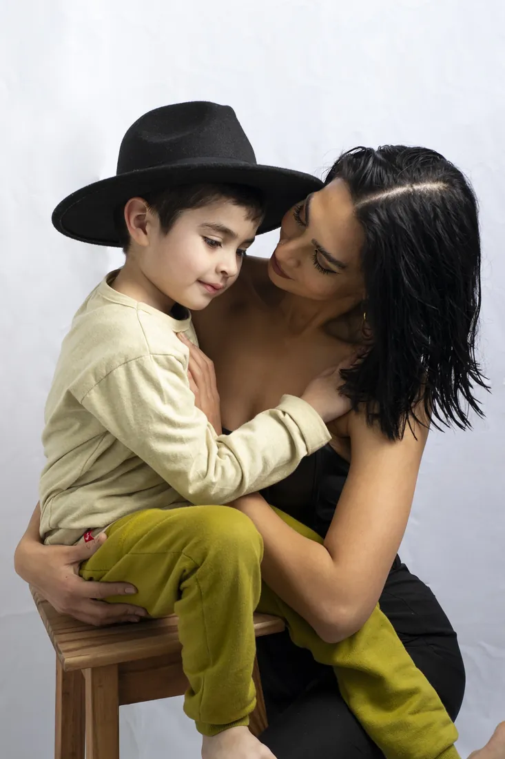 Una madre abraza a su hijo, que lleva un sombrero negro