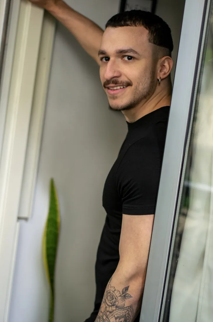 Hombre sonriente apoyado en el marco de una ventana